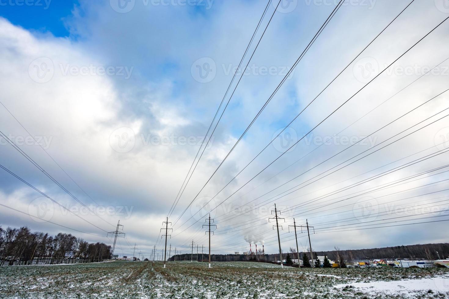 Silhouette of the high voltage electric pylon towers on the background of beautiful clouds. steaming pipes of a thermal power plant photo