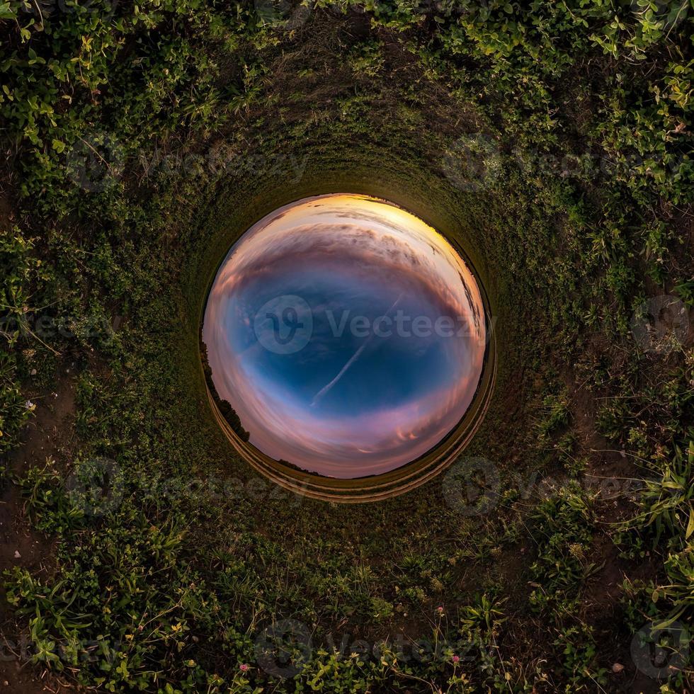 Little planet transformation of spherical panorama 360 degrees. Spherical abstract aerial view in field in nice evening with awesome beautiful clouds. Curvature of space. photo