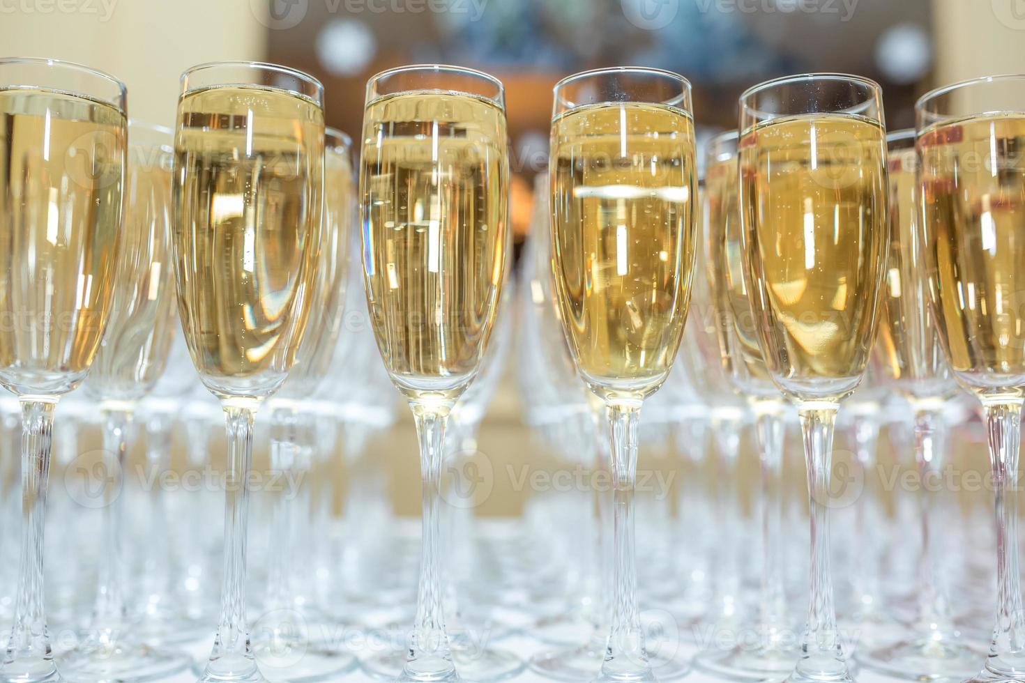 lot of blurred glasses with champagne on the reception party table on light background photo