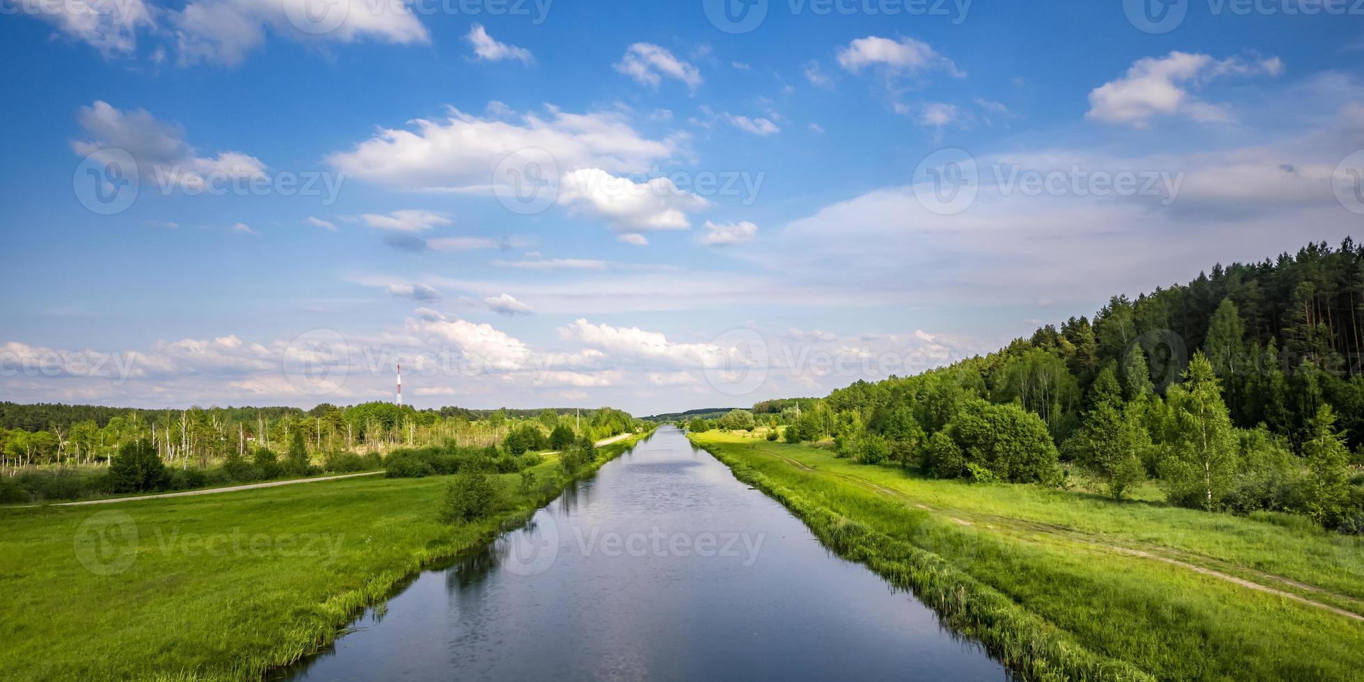 paisaje de un hermoso río ancho o canal en un día soleado con reflejo azul con hermosas nubes en el agua foto