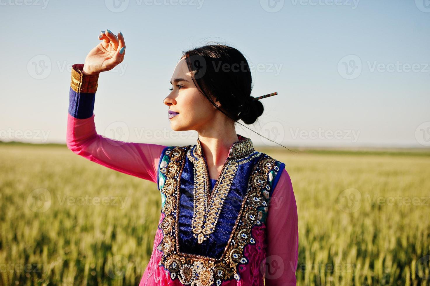 Tender indian girl in saree, with violet lips make up posed at field in sunset. Fashionable india model. photo