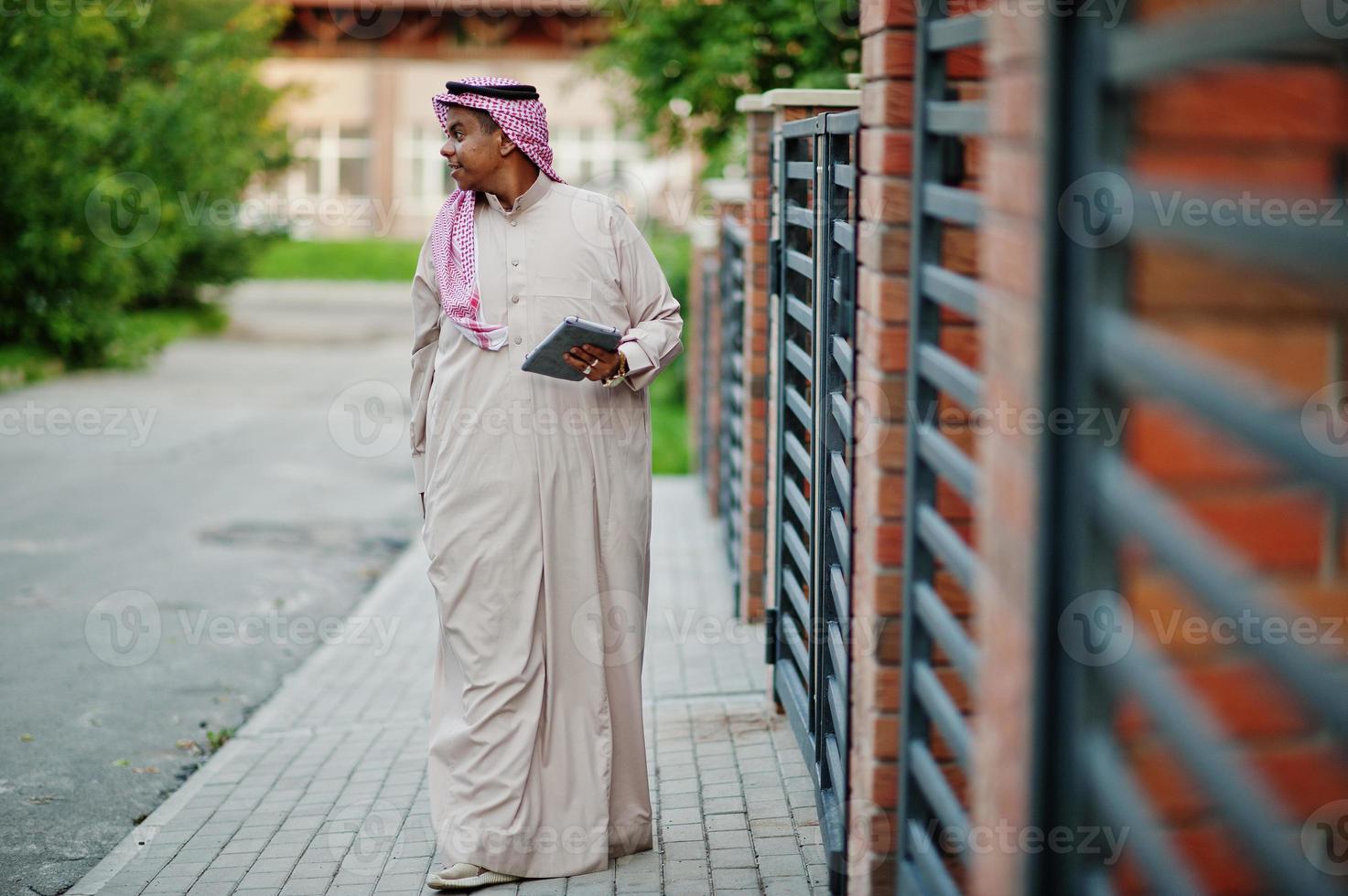 hombre árabe del Medio Oriente posó en la calle contra un edificio moderno con una tableta en las manos. foto