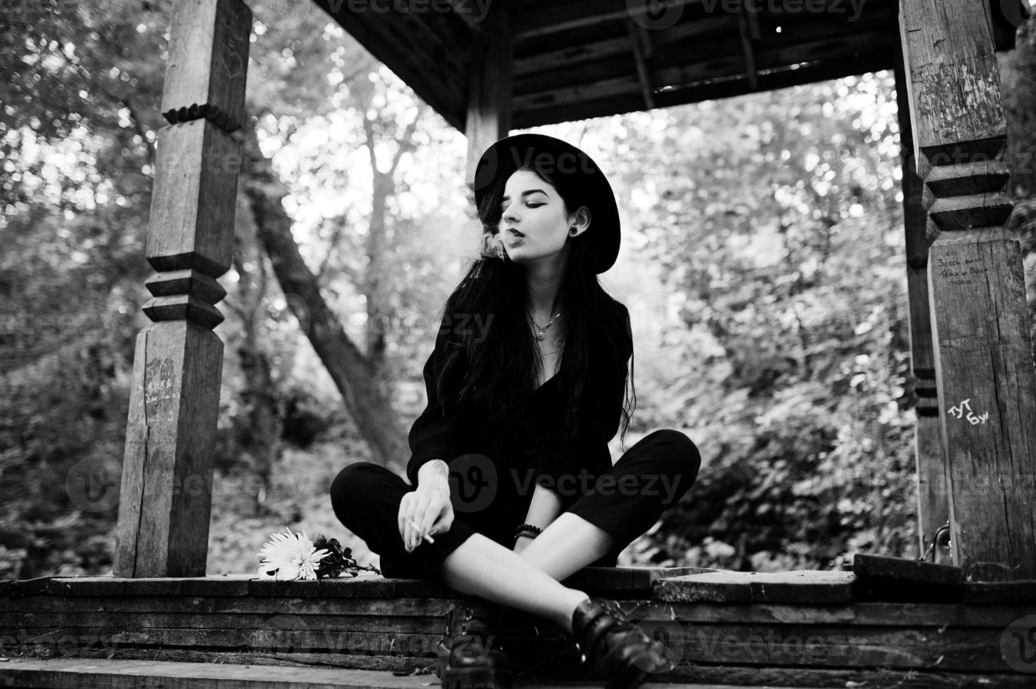 Sensual smoker girl all in black, red lips and hat. Goth dramatic woman smoking thin cigarette. Black and white portrait. photo