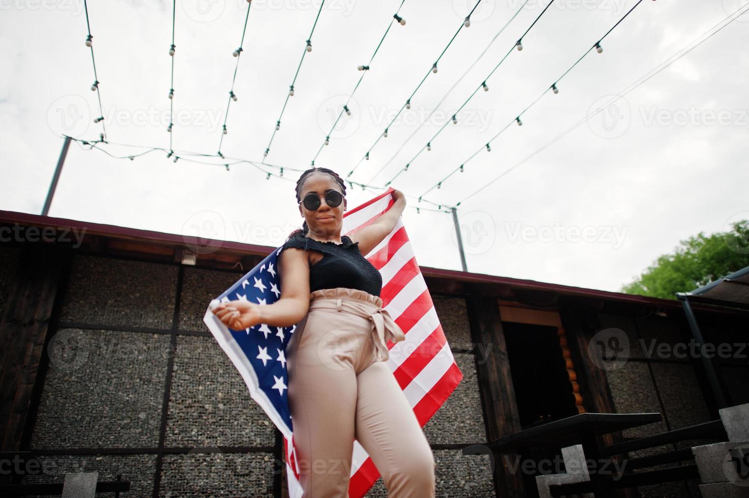 Stylish african american woman in sunglasses posed outdoor with usa flag. photo