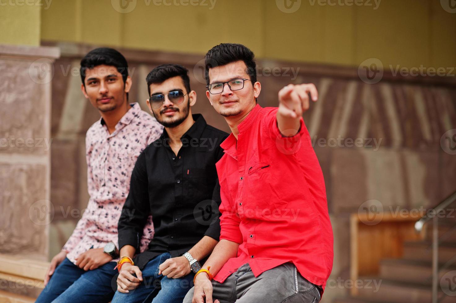Three indian guys students friends posed on street, one of men show finger. photo