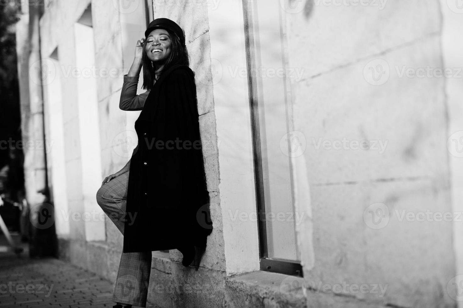 African american fashion girl in coat and newsboy cap posed at street. photo