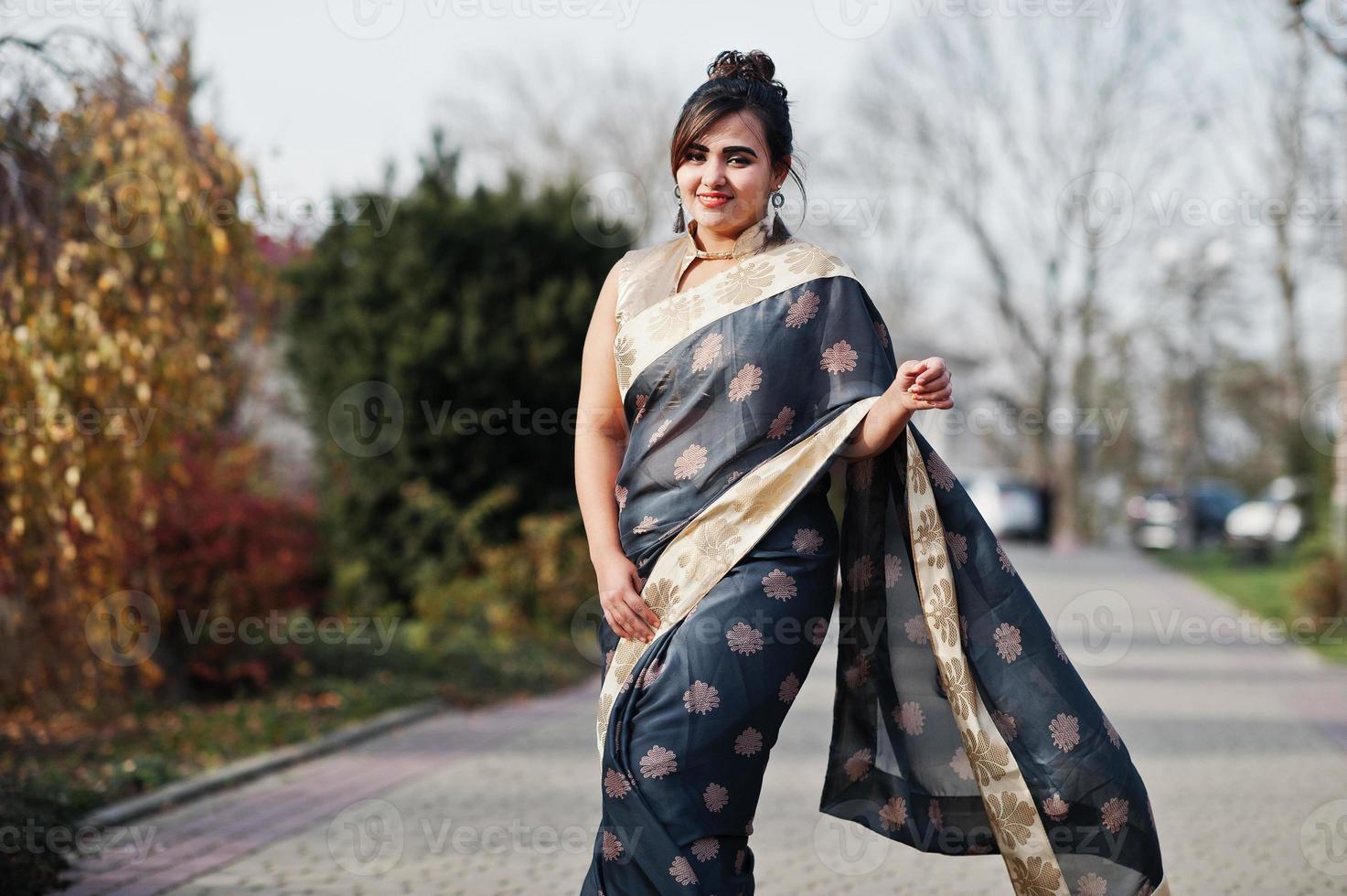 elegante morena chica india del sur de asia en sari caminando al aire libre. foto