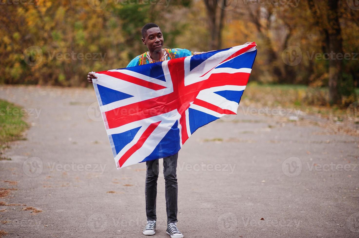 African man in africa traditional shirt on autumn park with Great Britain flag. photo