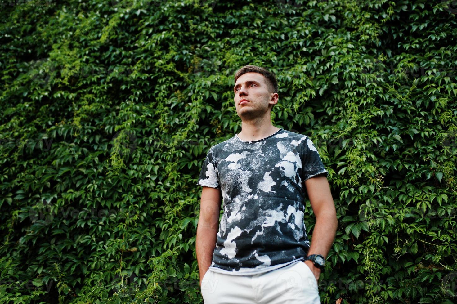Lifestyle portrait of handsome man posing against greenery wall. photo