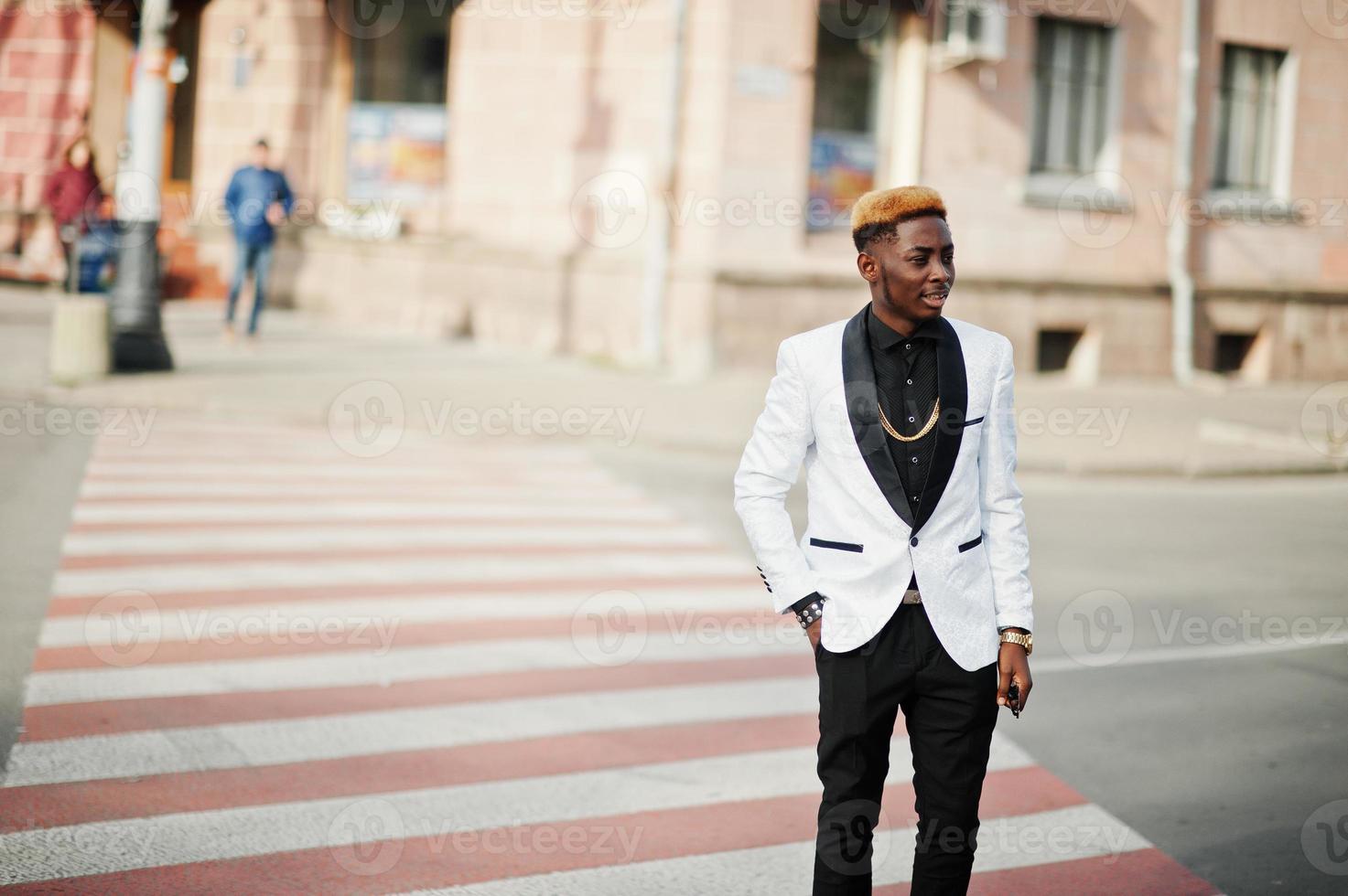 Chic handsome african american man in white suit walking on crosswalk. photo