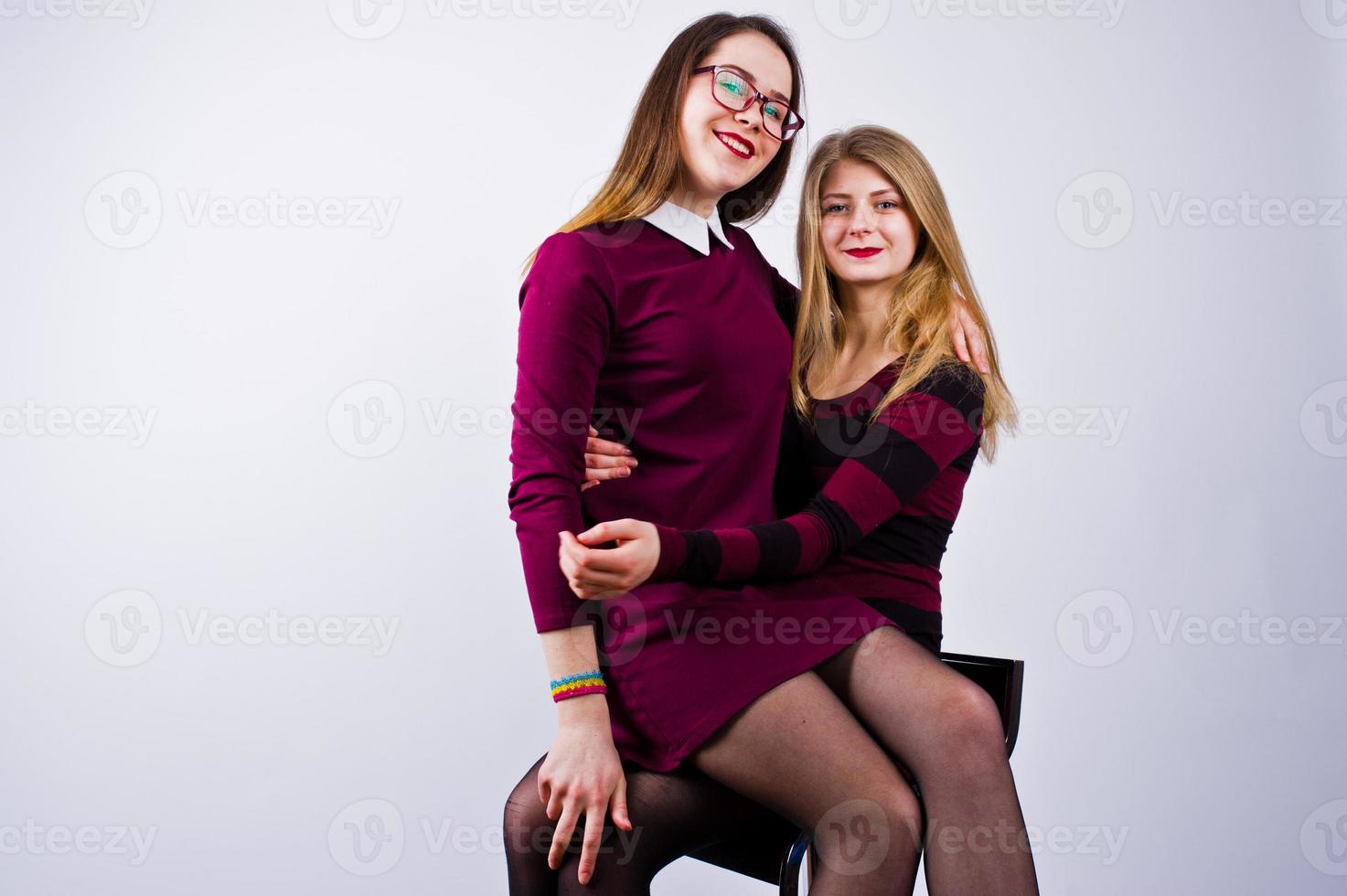 Girls in purple dresses having fun and posing on the chair in the studio. photo