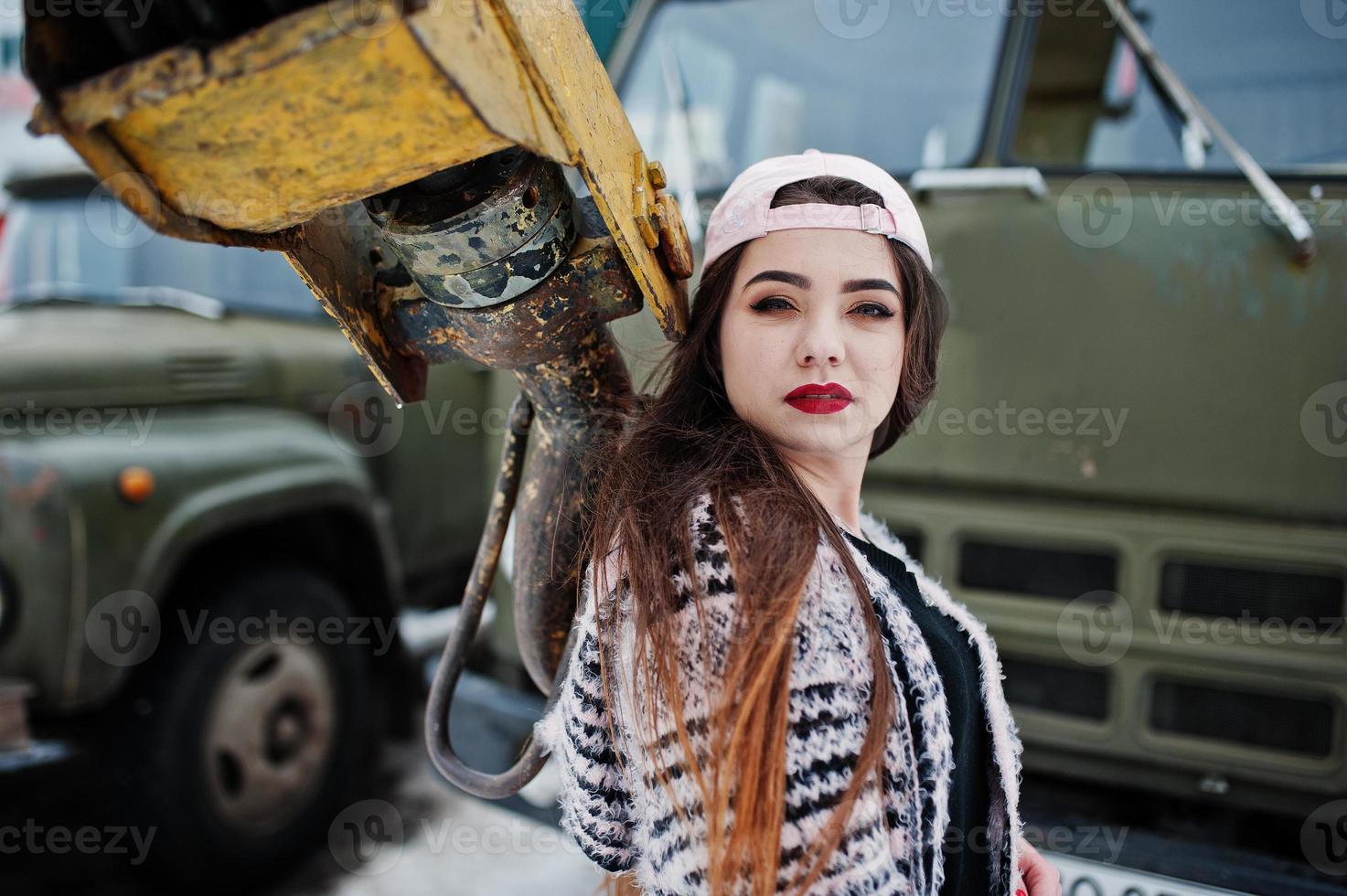 Brunette stylish casual girl in cap against old truck crane. photo