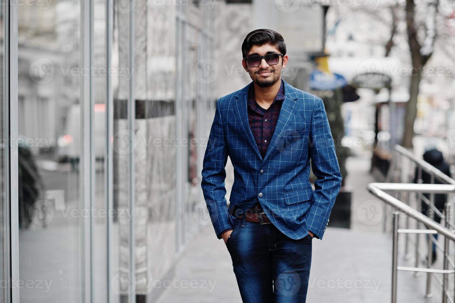 Young indian man on blue suit and sunglasses posed outdoor. photo