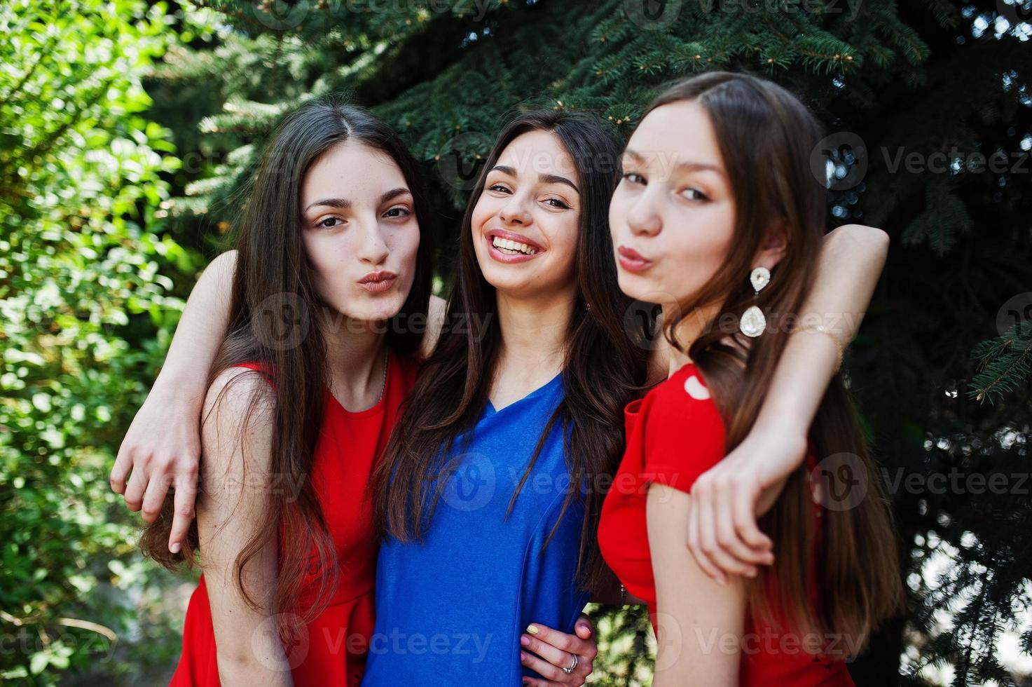 Three teenagers girl in blue and red dresses posed outdoor. photo