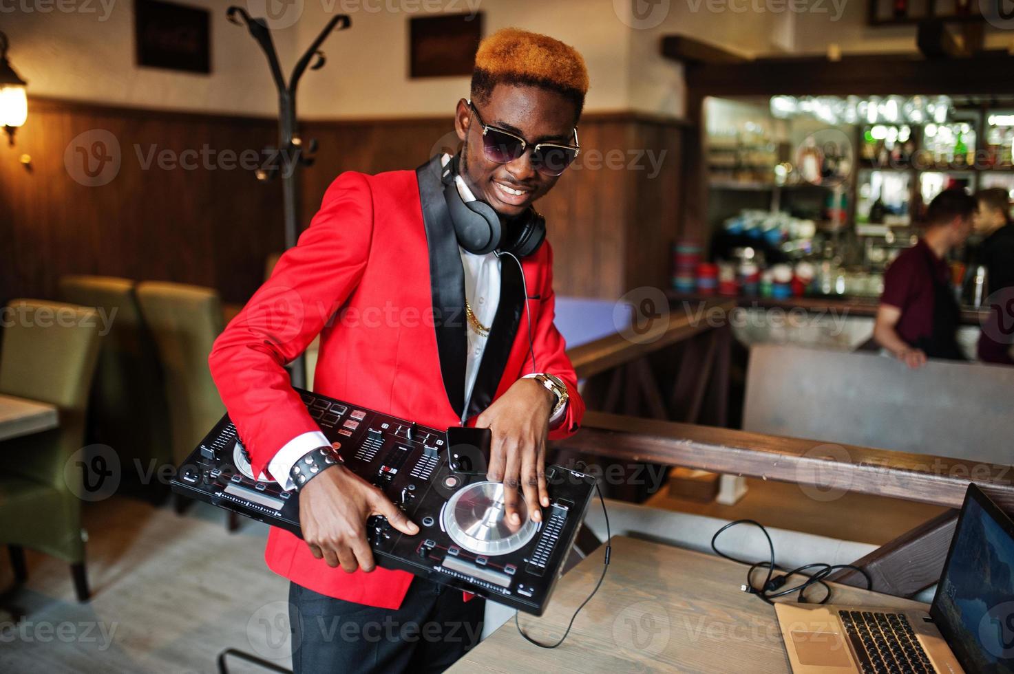 moda hombre afroamericano modelo dj en traje rojo con controlador de dj. foto