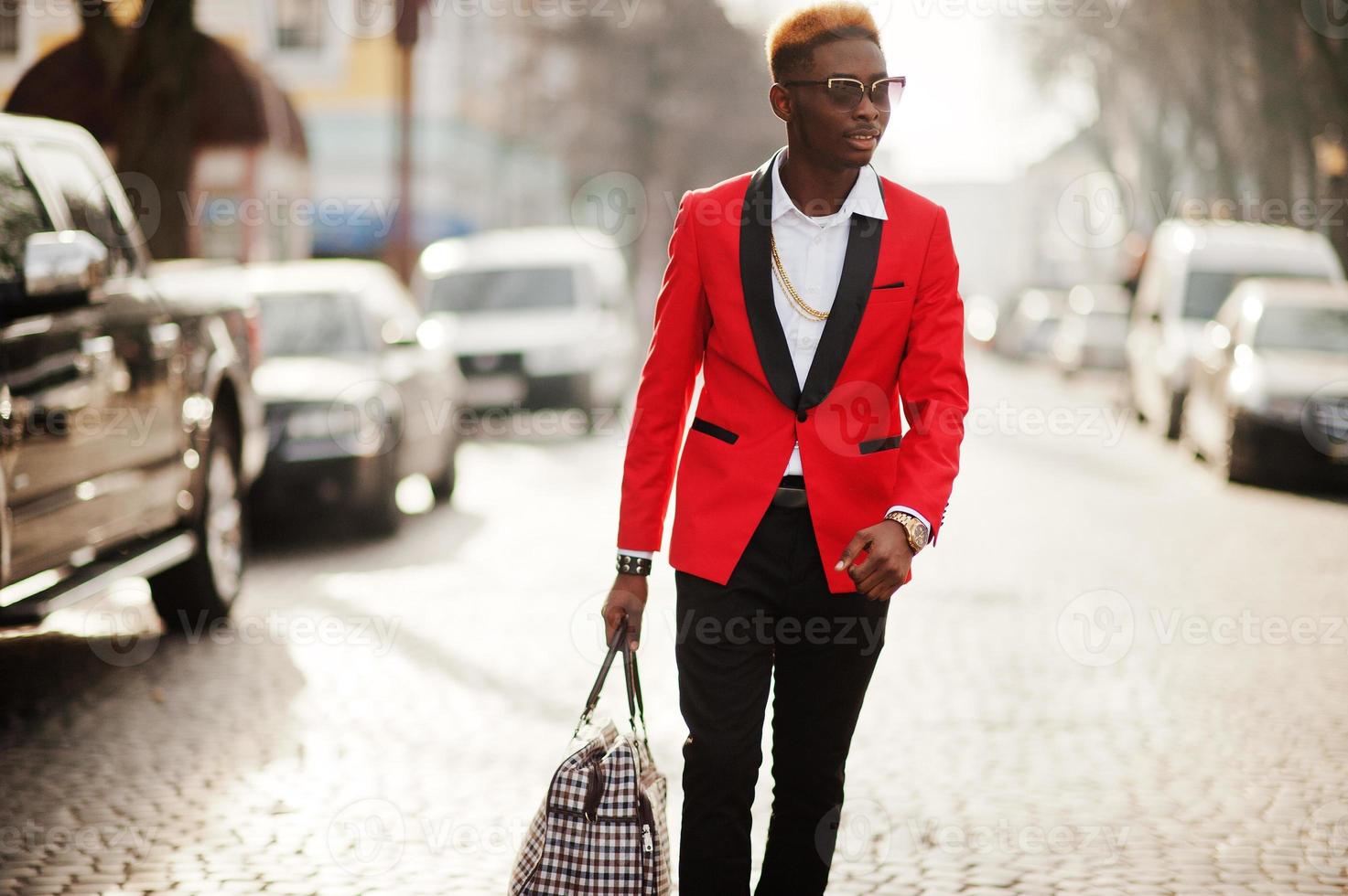 Fashion african american man model at red suit, with highlights hair and handbag posed at street. photo