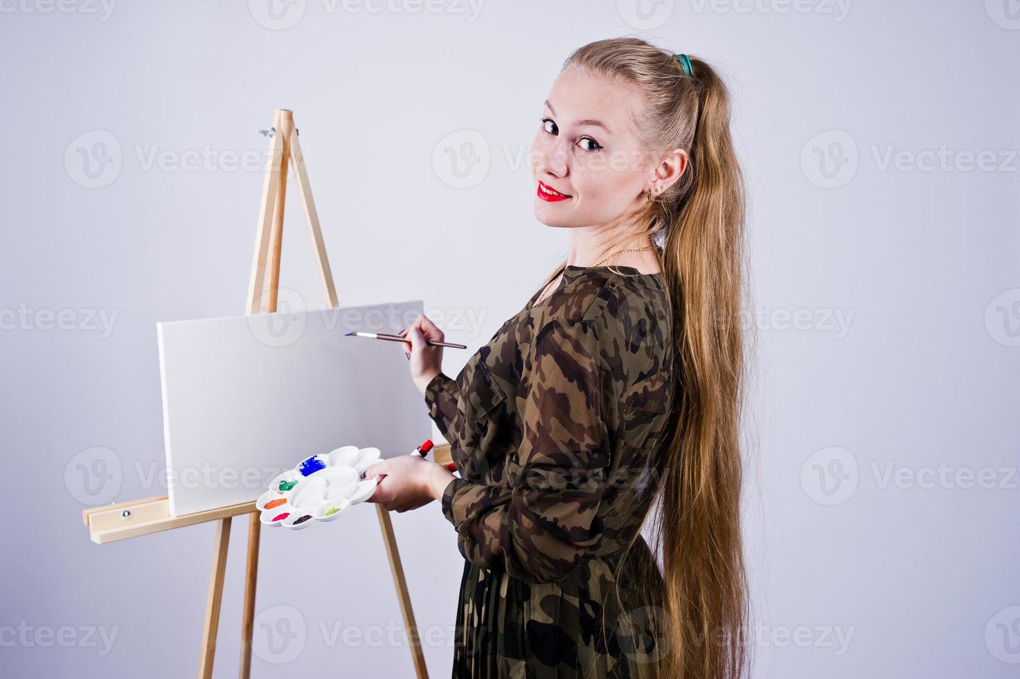 Beautiful woman artist painter with brushes and oil canvas posing in studio isolated on white. photo