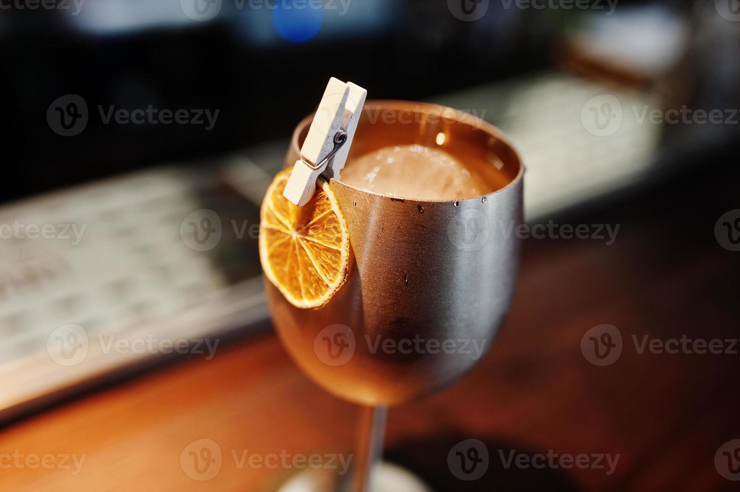 Alcoholic cocktail with ice in silver glass on bar table. photo