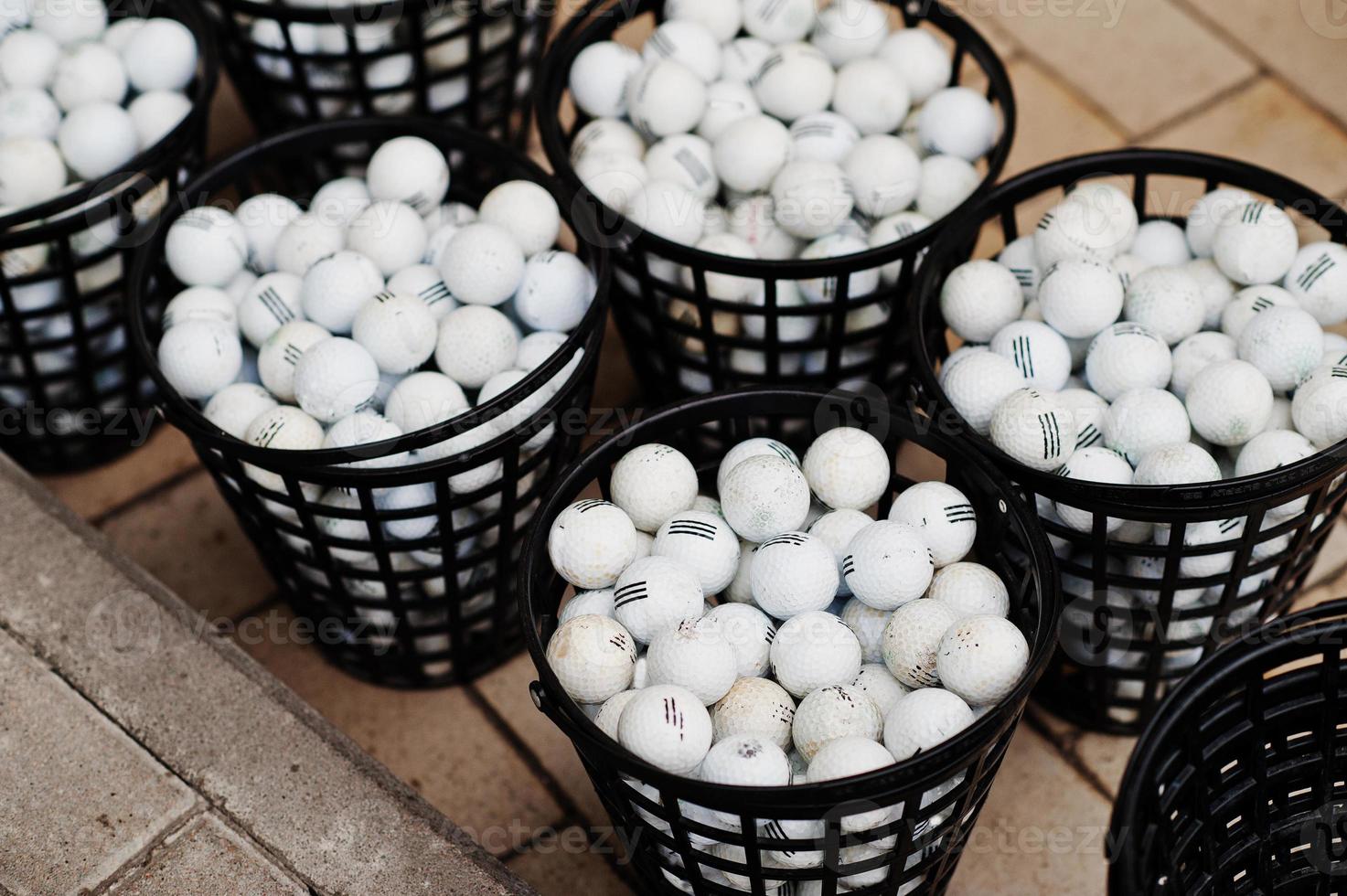 Golf balls in a baskets on pavement. photo