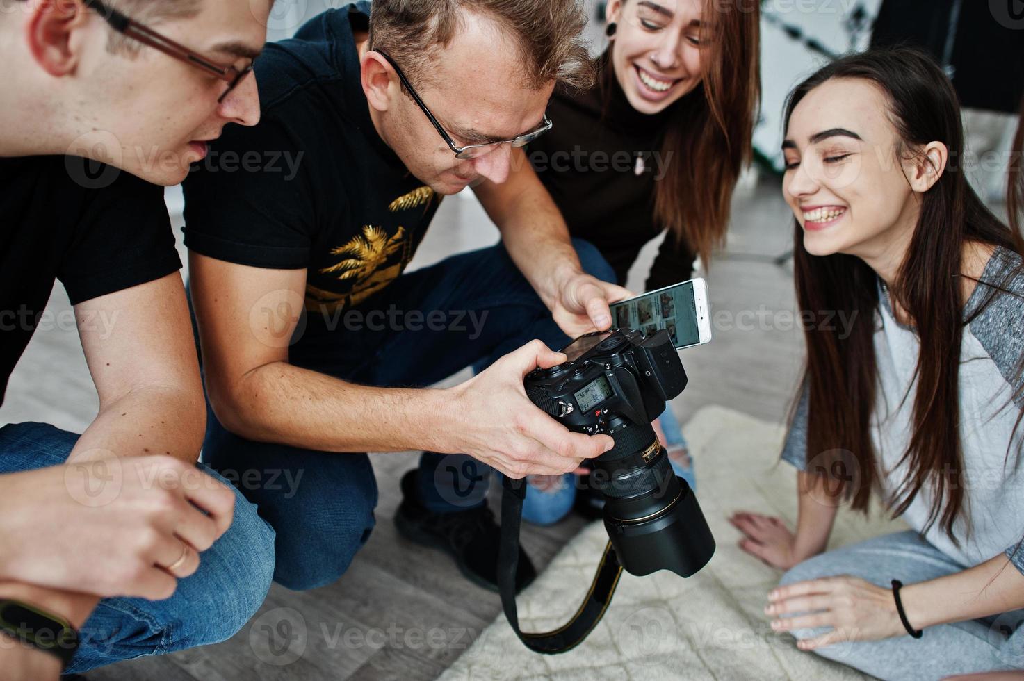 The team of photographers showing pictures on screen of camera for twins models girls on studio. Professional photographer on work. photo