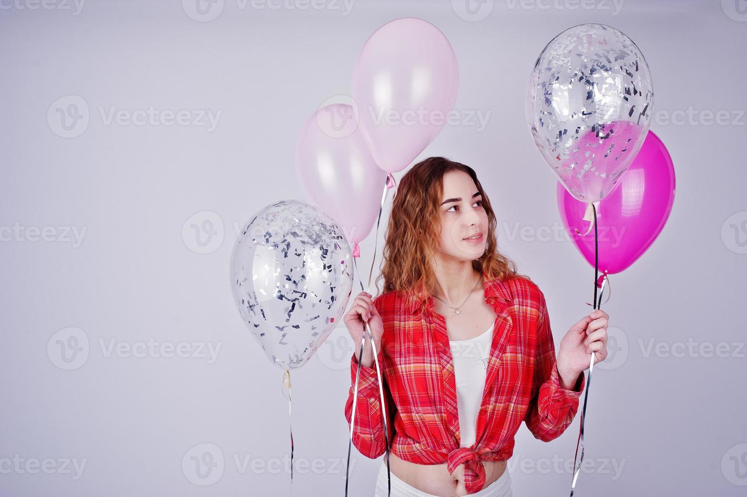 jovencita con camisa roja a cuadros y pantalón blanco con globos sobre fondo blanco en el estudio. foto