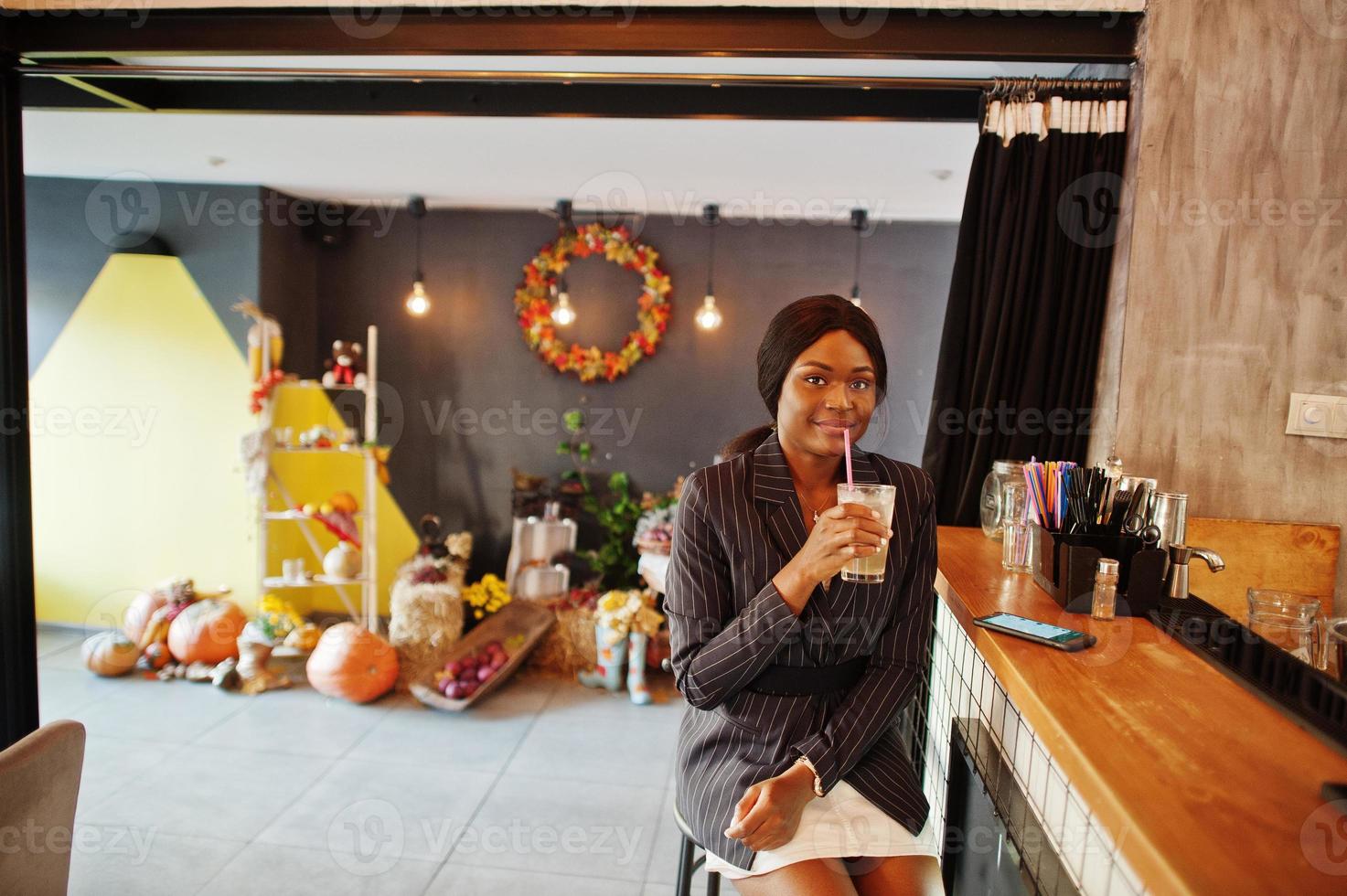 African american businesswoman drinking cocktail lemonade in cafe at the bar. Black girl having rest with mobile phone. photo