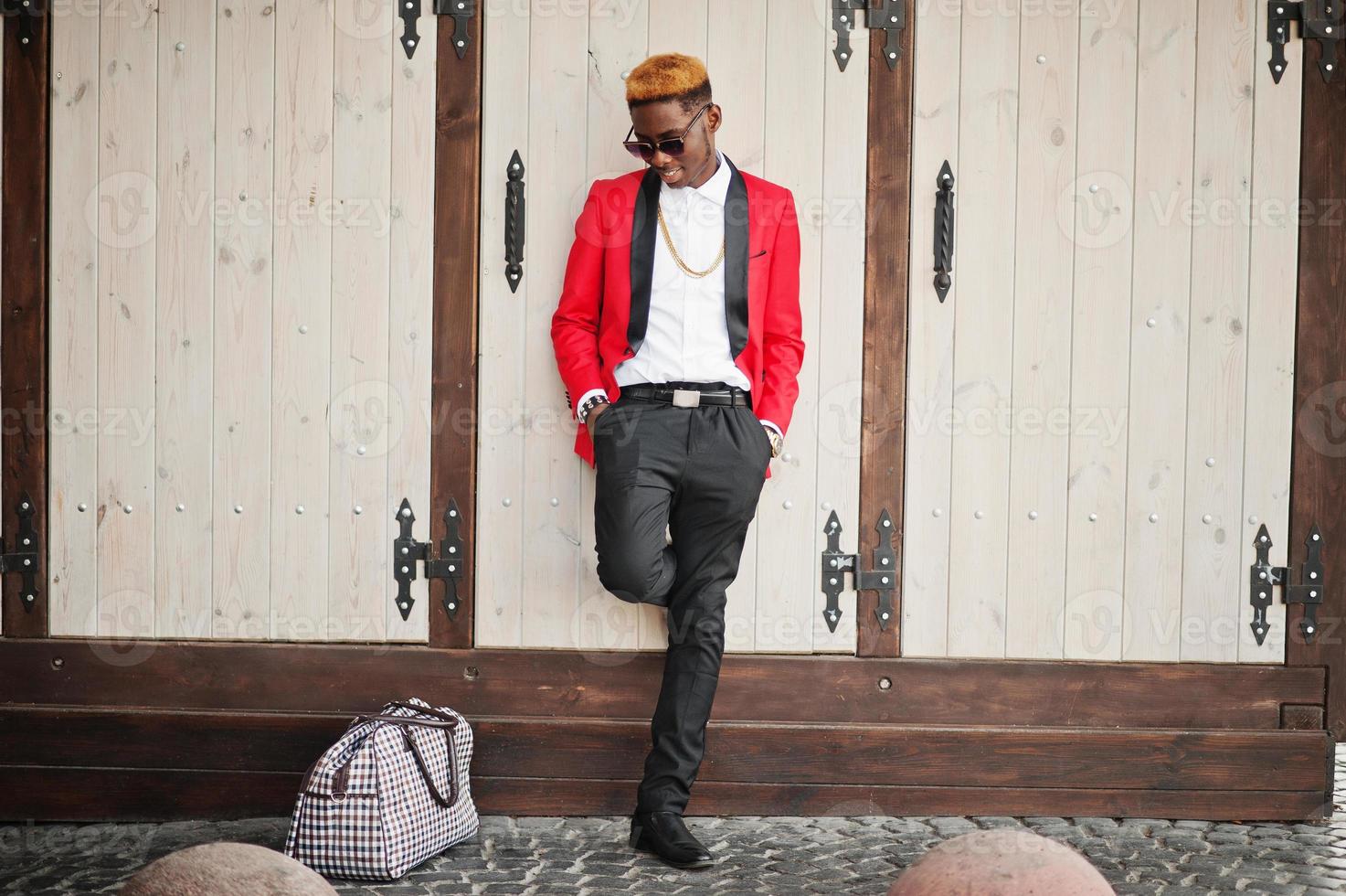 Fashion african american man model at red suit, with highlights hair and handbag posed at street. photo