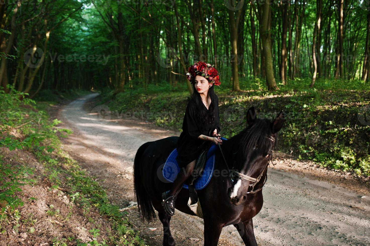 Mystical girl in wreath wear in black at horse in wood. photo