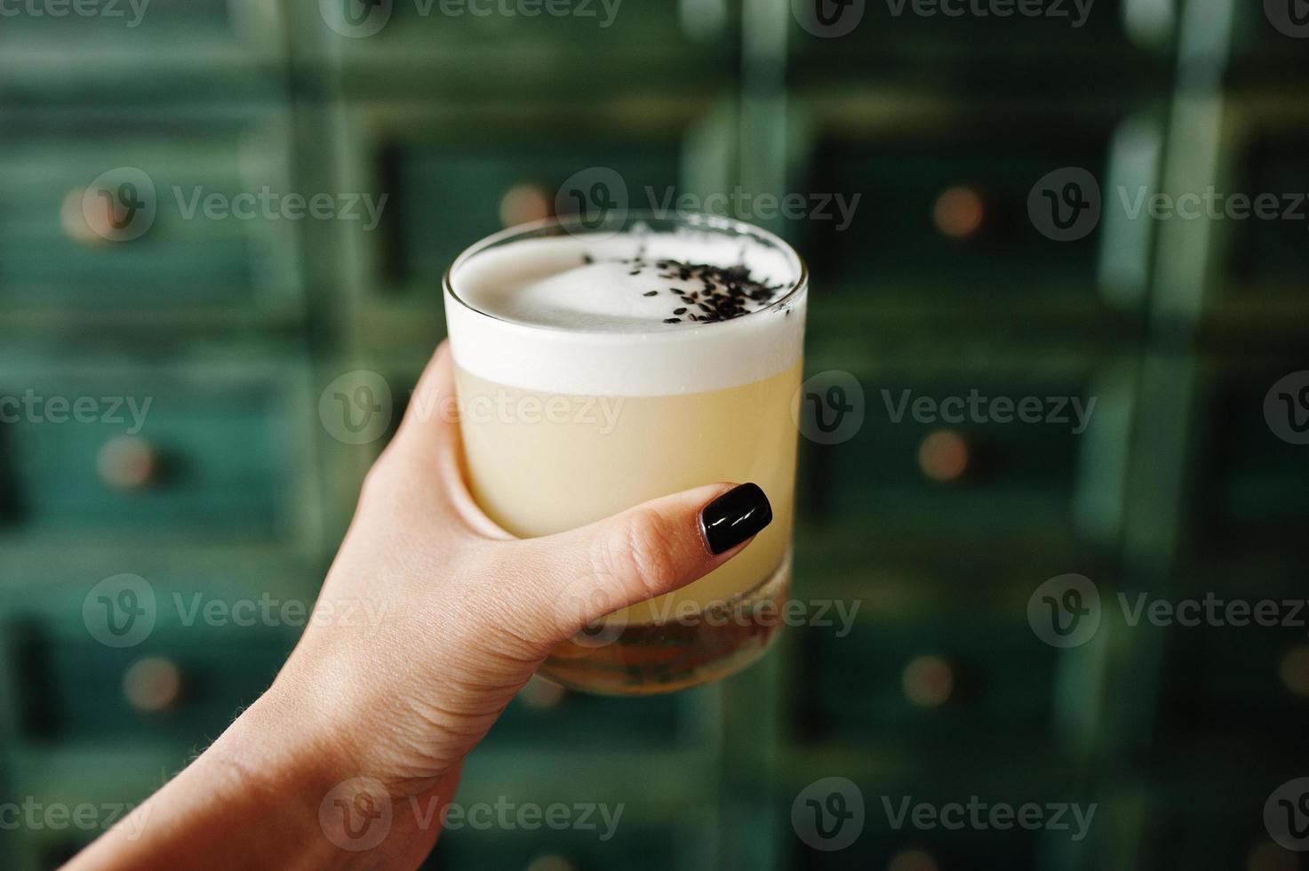 Alcoholic cocktail in glass on hand of barman. photo