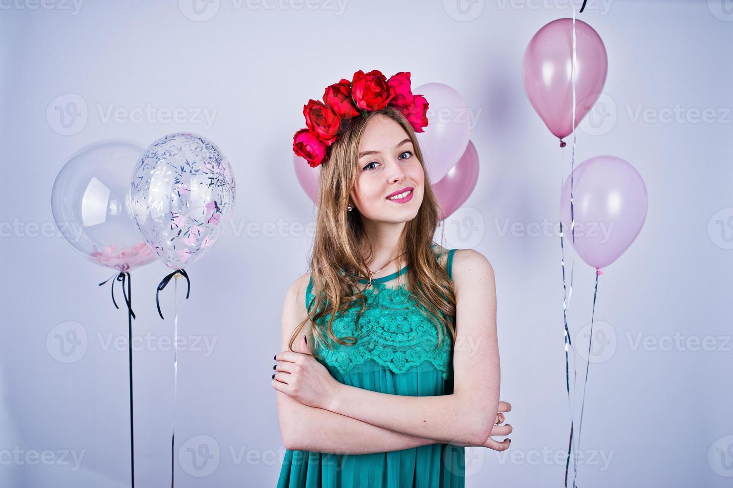 Happy girl in green turqoise dress and wreath with colored balloons isolated on white. Celebrating birthday theme. photo