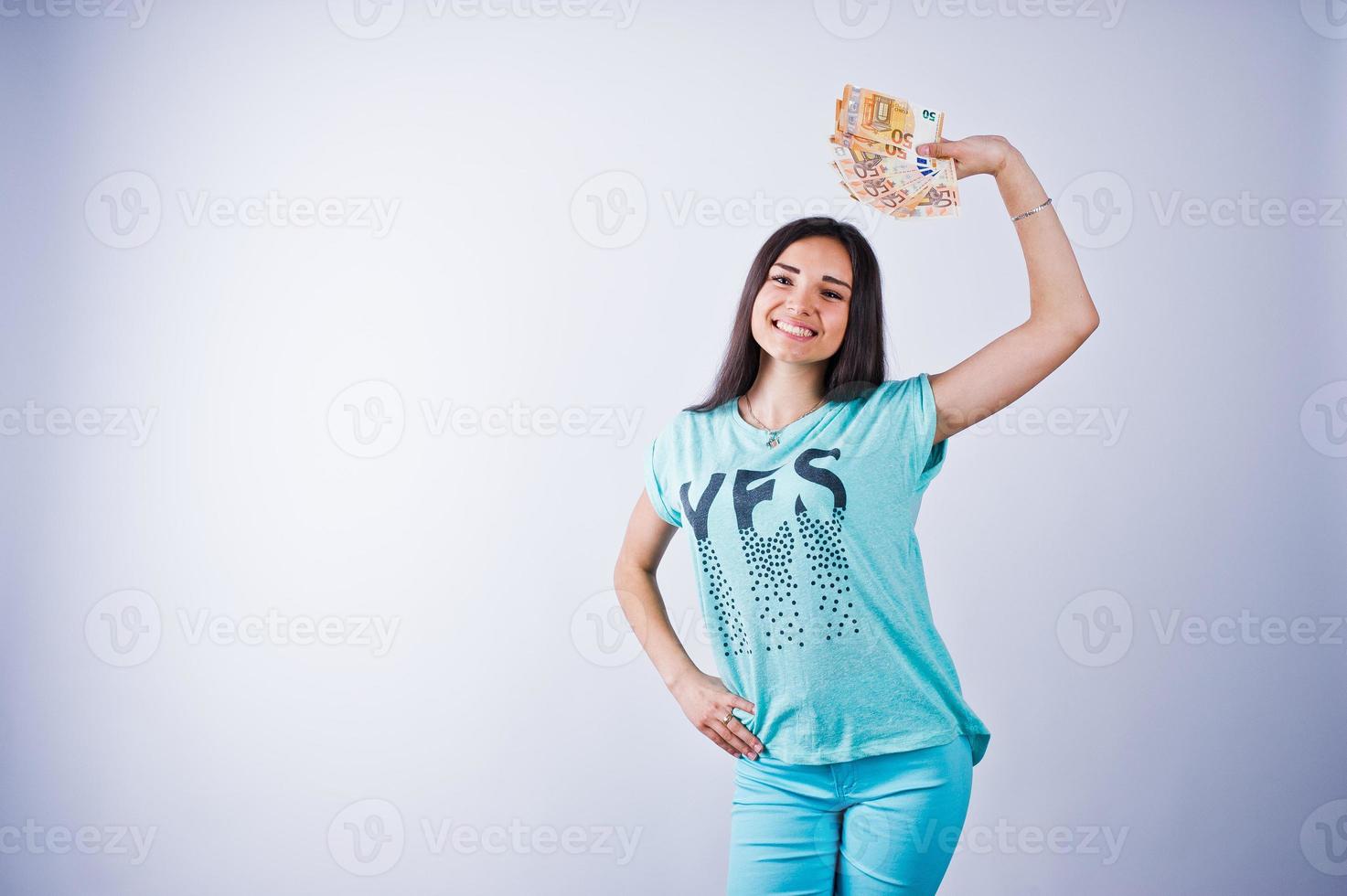 Portrait of an attractive girl in blue or turquoise t-shirt and trousers posing with a lot of money in her hand. photo
