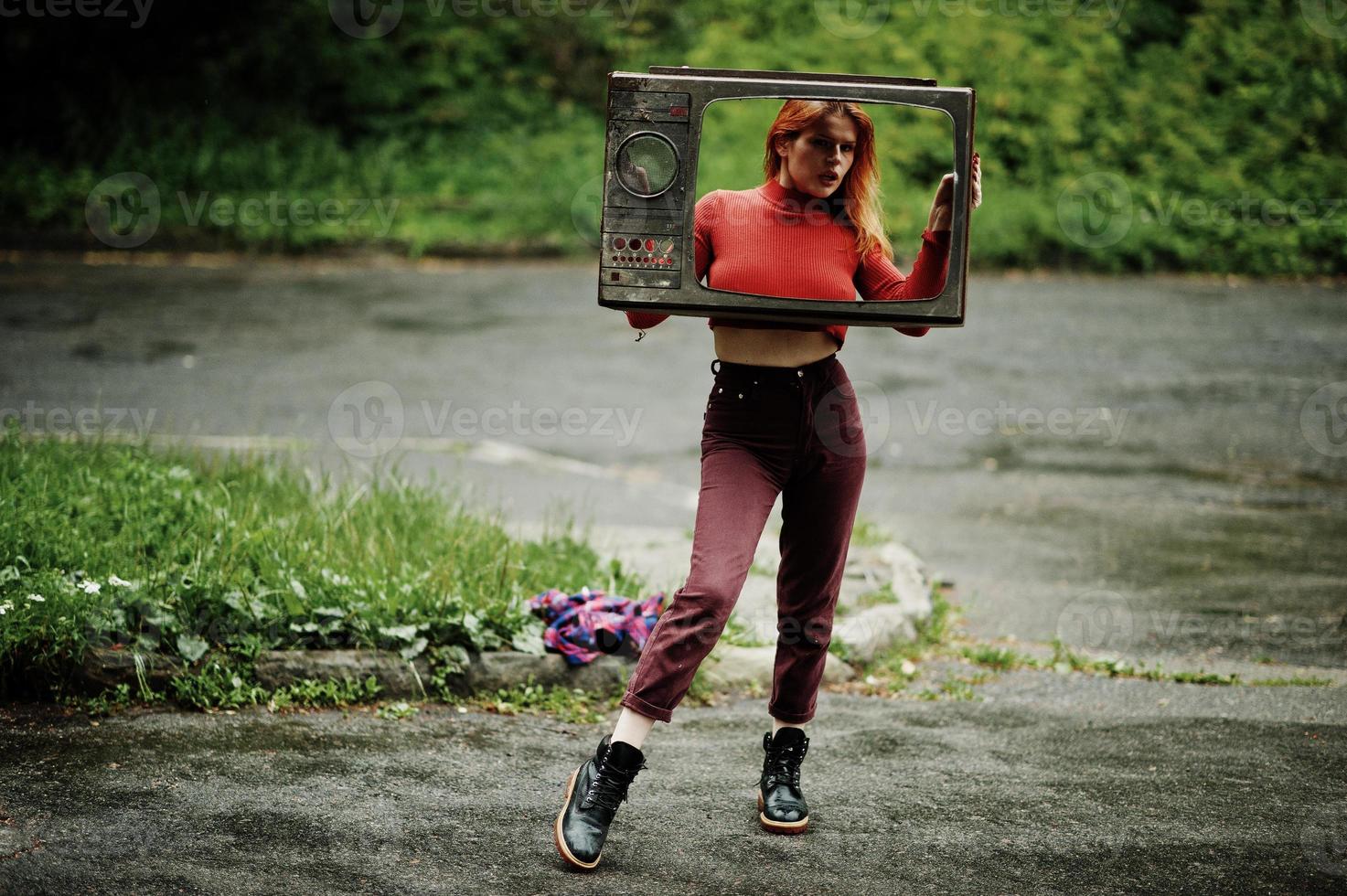 retrato de moda de chica sexy pelirroja al aire libre. modelo atractiva mujer dramática con caja de tv antigua. foto