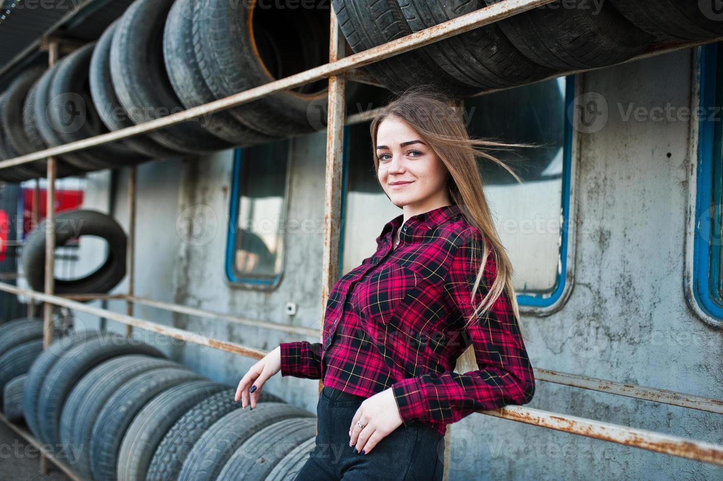 Young hipster girl in checkered shirt at tire fitting zone. photo