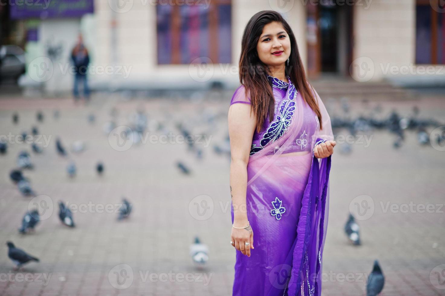 Indian hindu girl at traditional violet saree posed at street against doves. photo