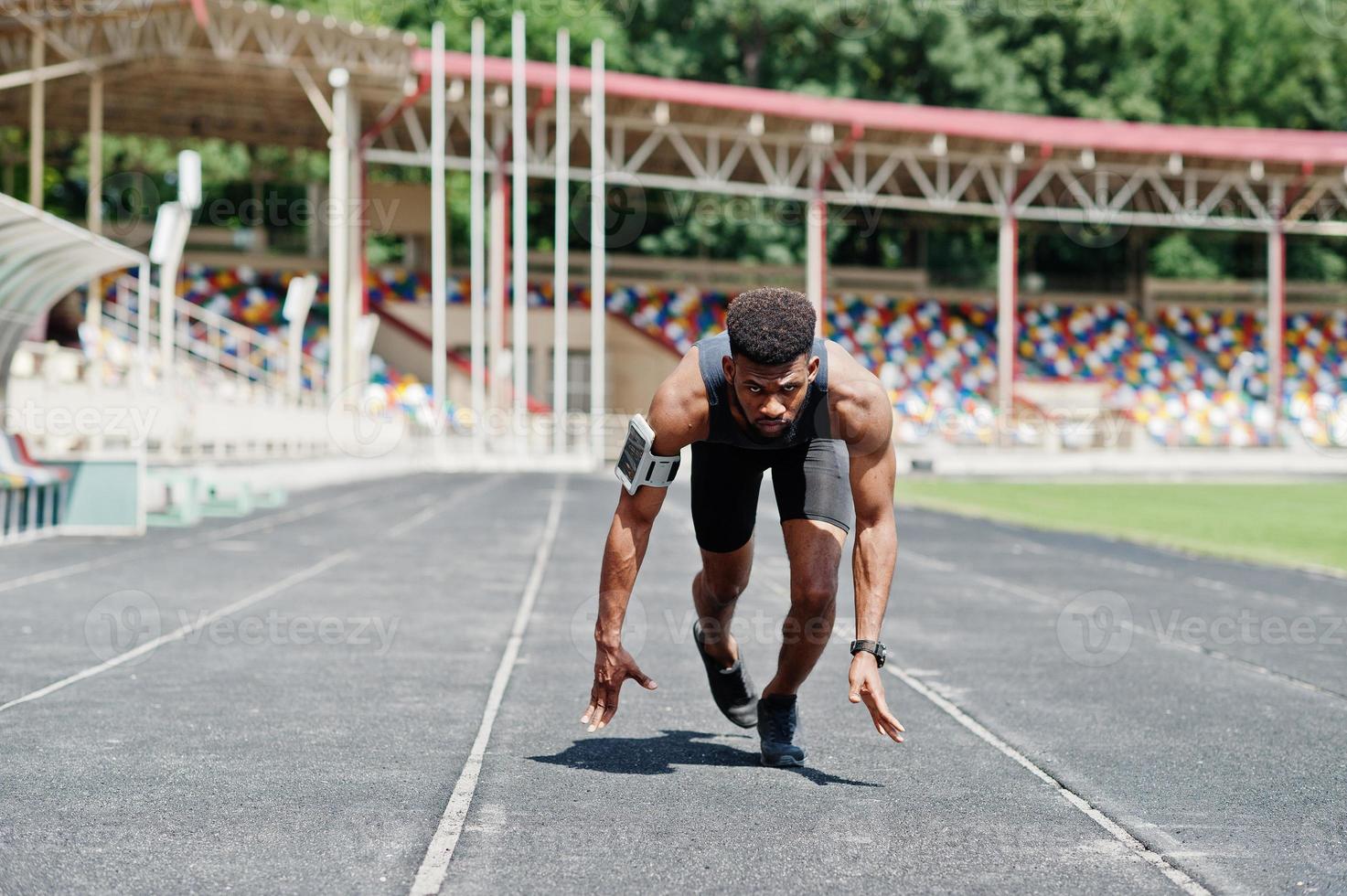 African american male athlete in sportswear racing alone down a running track at stadium. photo