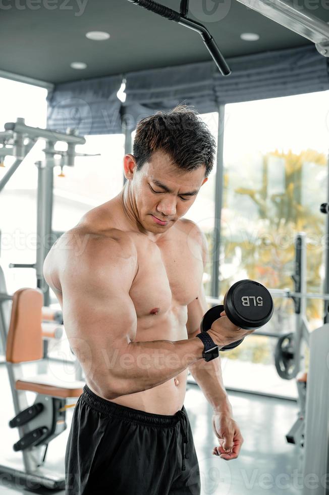 Asian men exercise by lifting weights or lifting dumbbells. Asian bodybuilder fitness concept photo