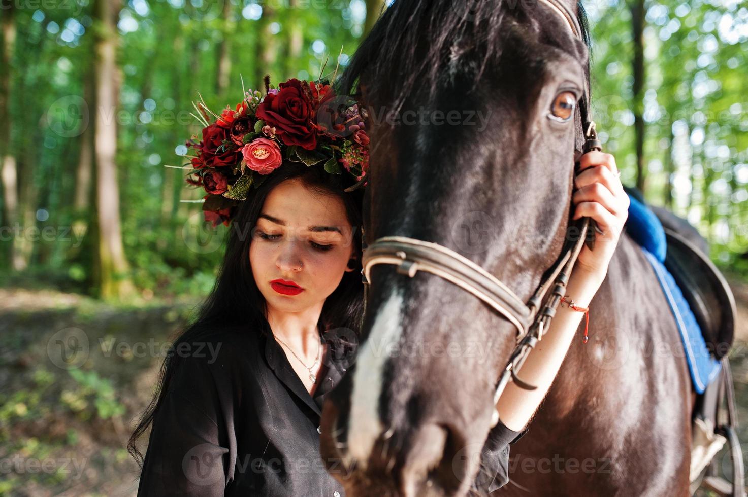 chica mística en ropa de corona en negro con caballo en madera. foto