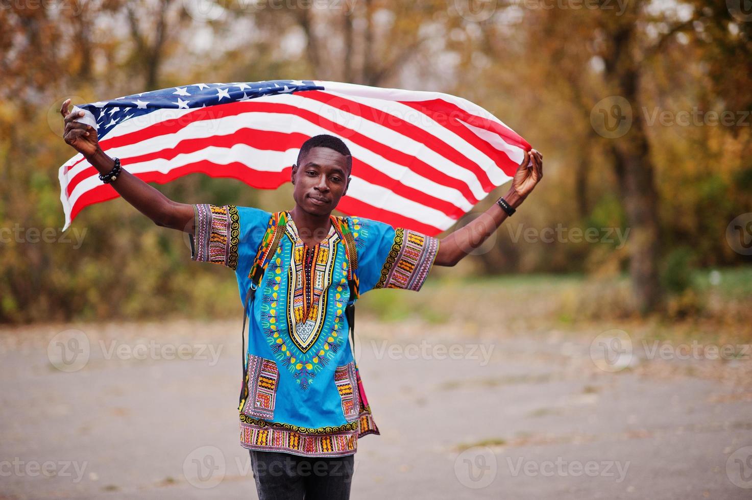African man in africa traditional shirt on autumn park with USA flag. photo