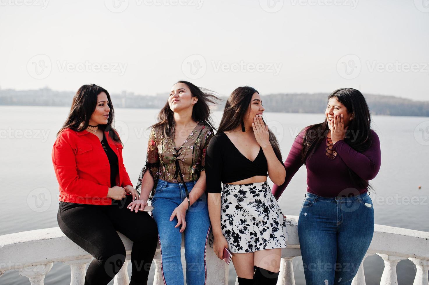 Group of four happy and pretty latino girls from Ecuador posed against lake side. photo