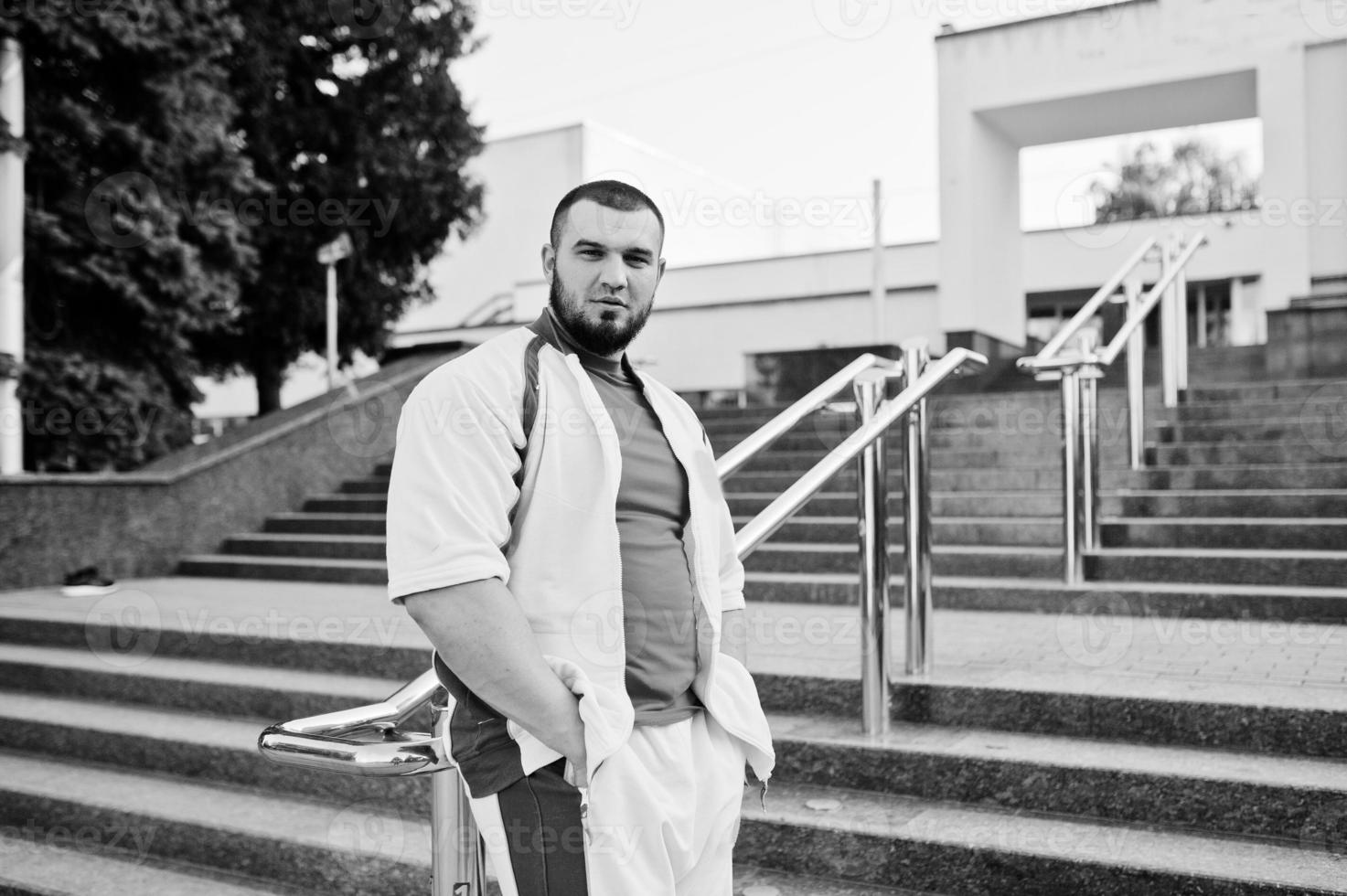 Young brutal bearded muscular man wear on white sport suit with red shirt. photo