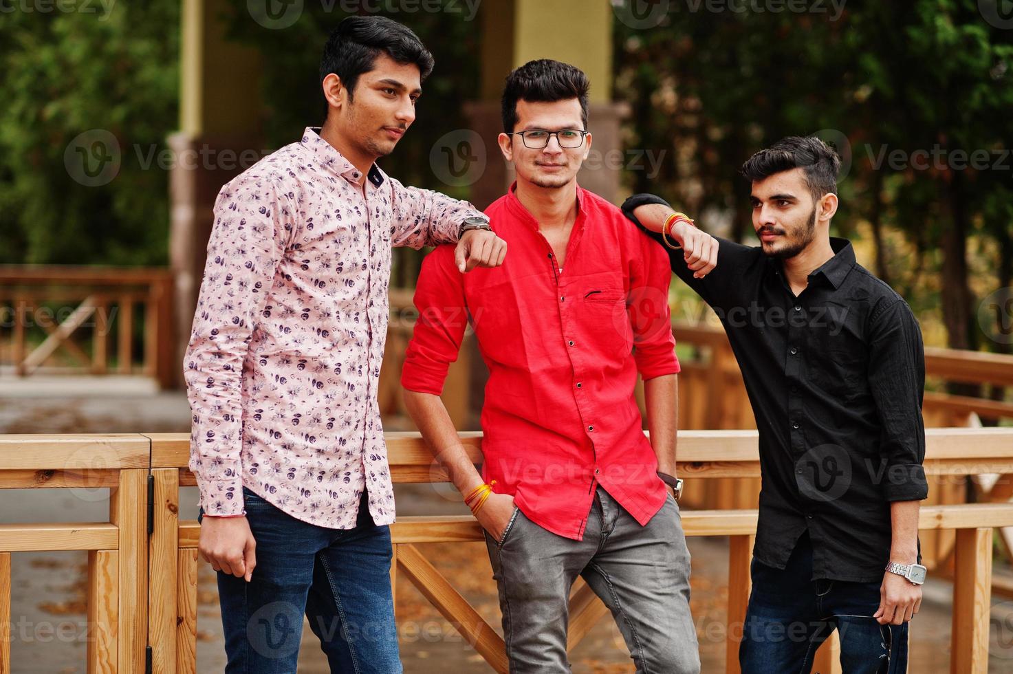 Three indian guys students friends walking on street. photo