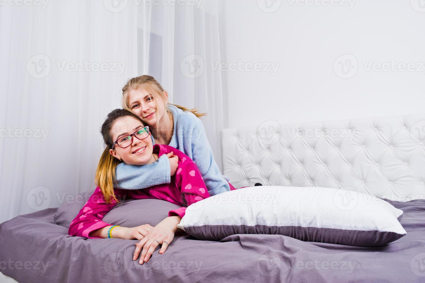 dos amigas en pijama divirtiéndose en la cama en la habitación. foto