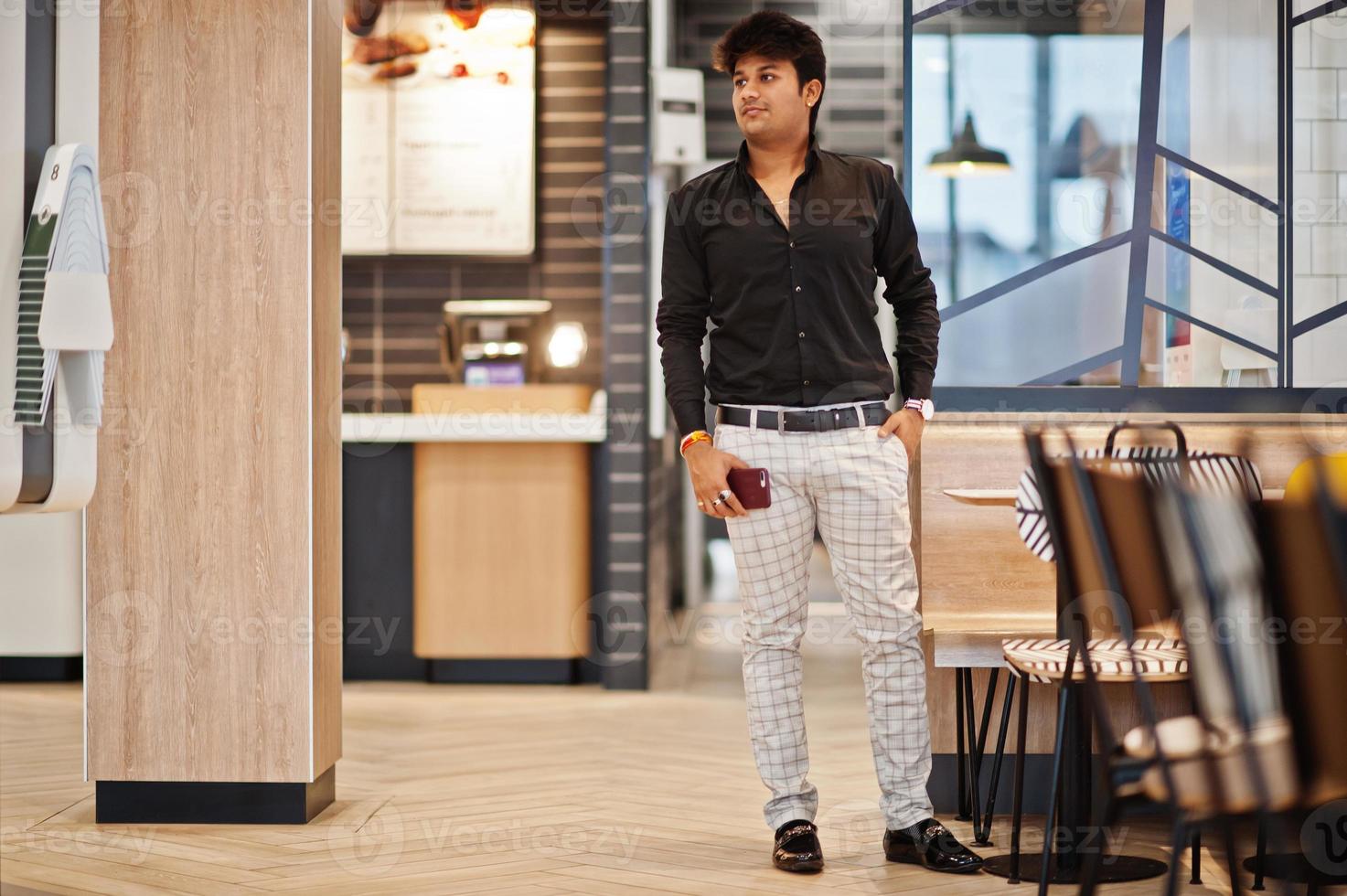 Stylish indian man posed at fast food cafe with mobile phone at hand. photo