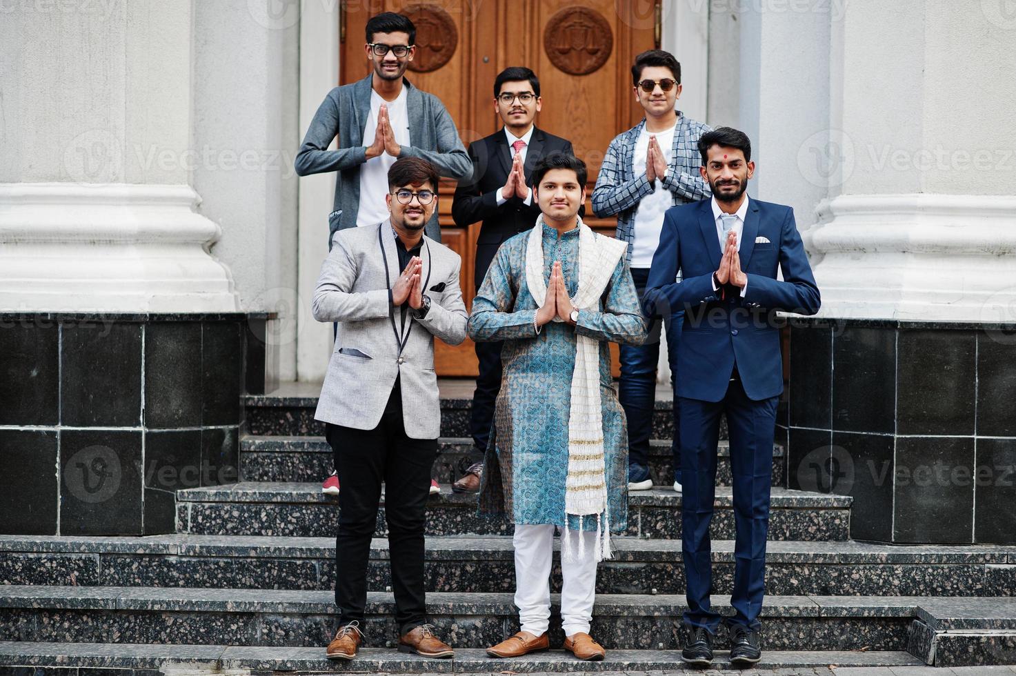 grupo de seis hombres indios del sur de asia con ropa tradicional, informal y de negocios parados en las escaleras y mostrando el signo de las manos de namaste. foto