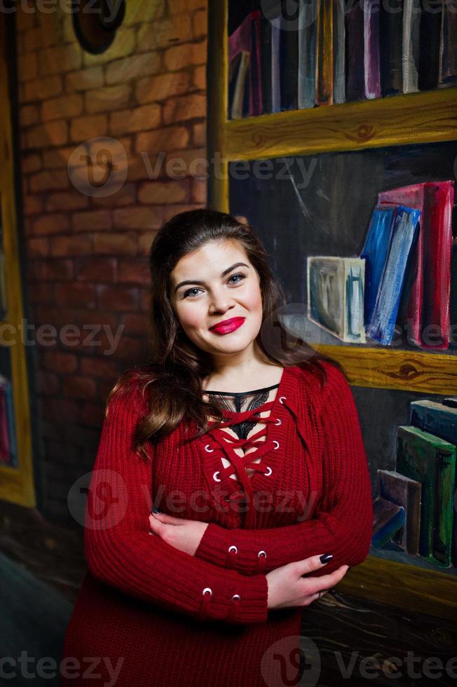 Brunette plus size model against wall like library. photo