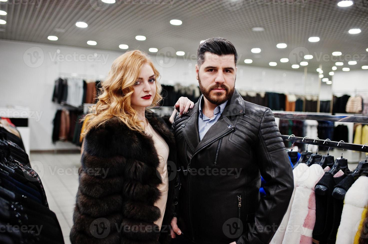 Elegance blonde girl in fur coat and stylish turkish man at the store of fur coats and leather jackets. photo