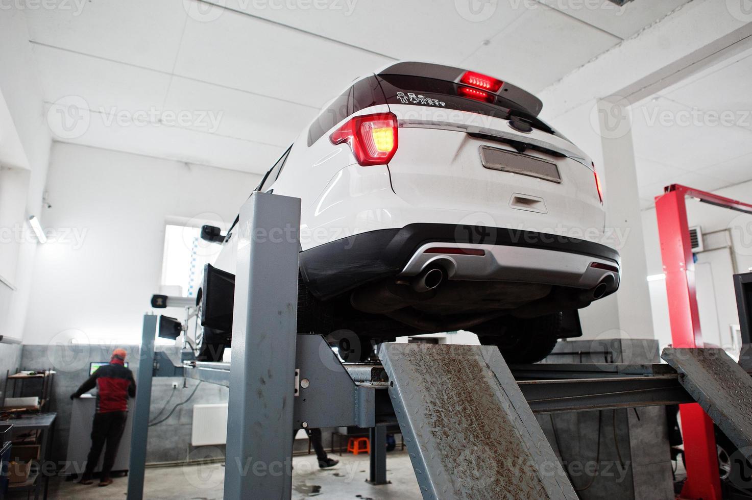 American SUV car on stand for wheels alignment camber check in workshop of service station. photo