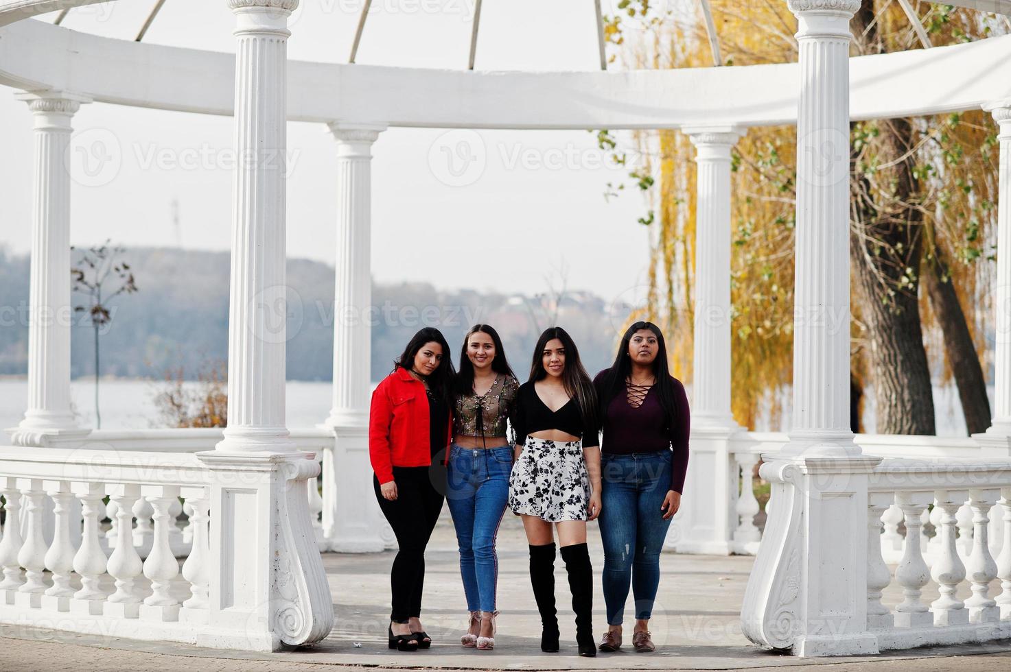 Group of four happy and pretty latino girls from Ecuador posed at street against ancient arch. photo