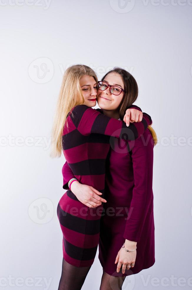 Portrait of two female friends in cherry dresses posing in the studio. photo