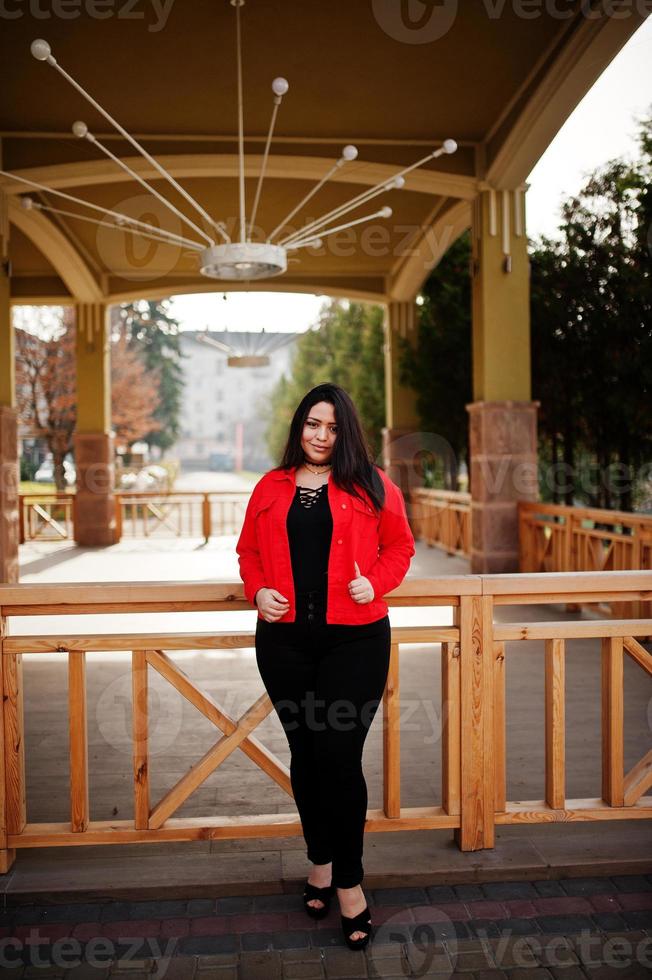 bonita chica modelo latina de ecuador usa chaqueta negra y roja posada en la calle. foto